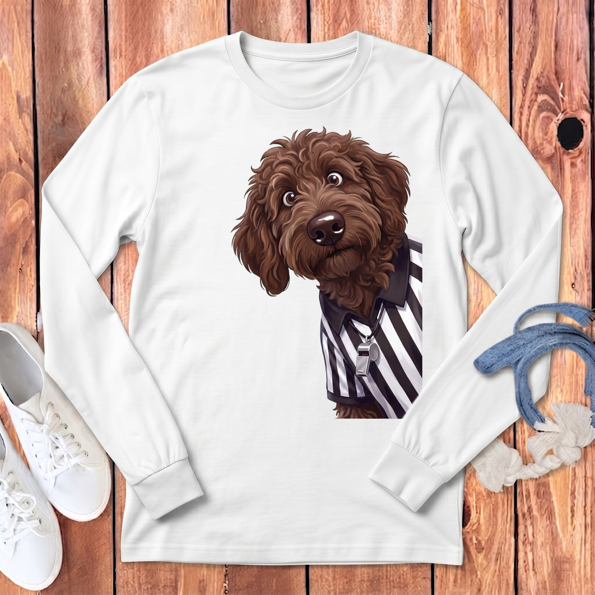 Brown doodle dog wearing a referee shirt with a whistle on a white long-sleeve shirt.