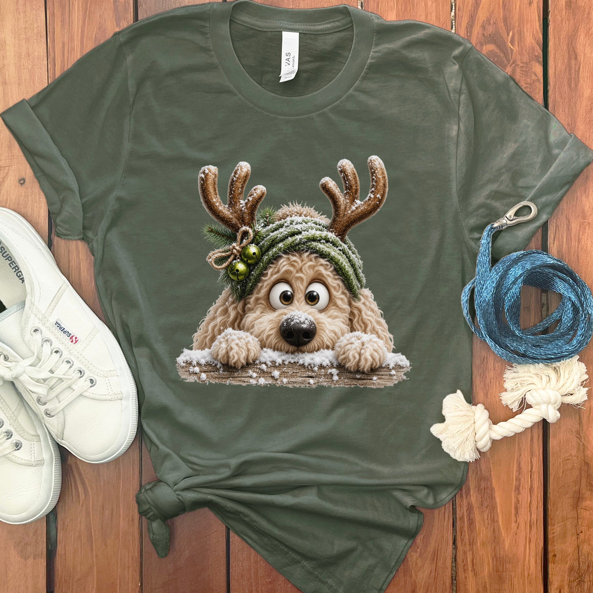 Fluffy dog in reindeer antlers and beanie peeks over wooden fence.