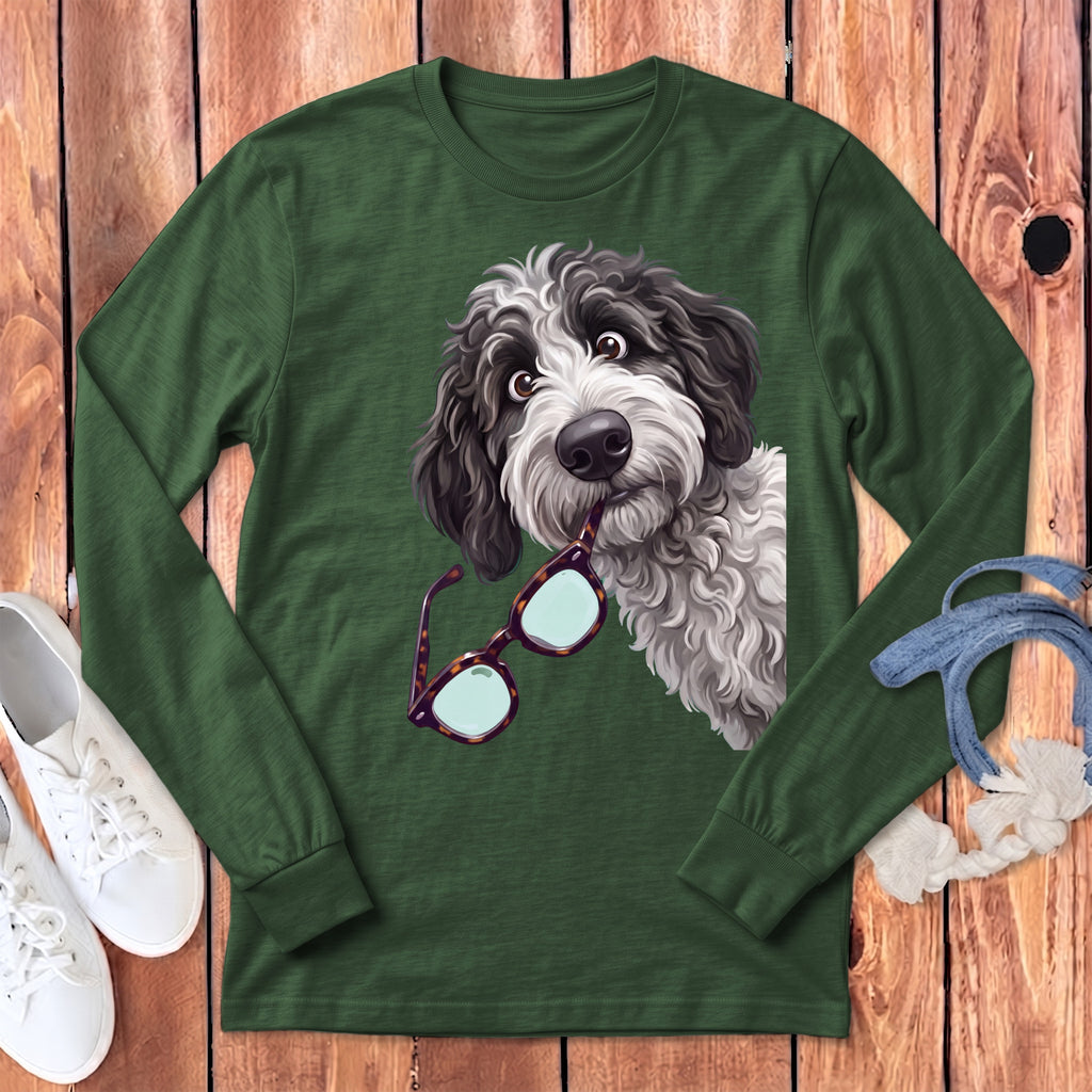 A dark green long-sleeve t-shirt features a graphic of a fluffy black and white dog holding glasses in its mouth.