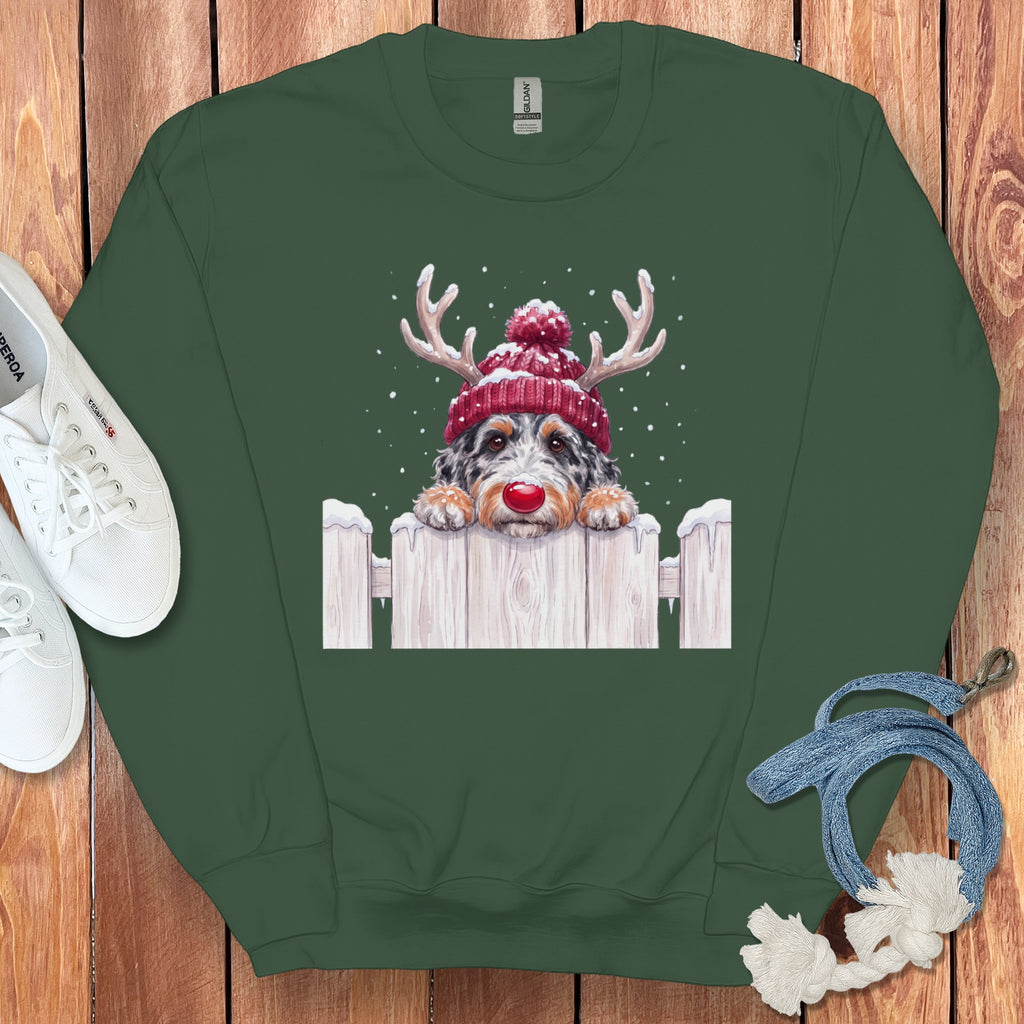 Green sweatshirt with dog wearing Santa hat and antlers on a white picket fence.