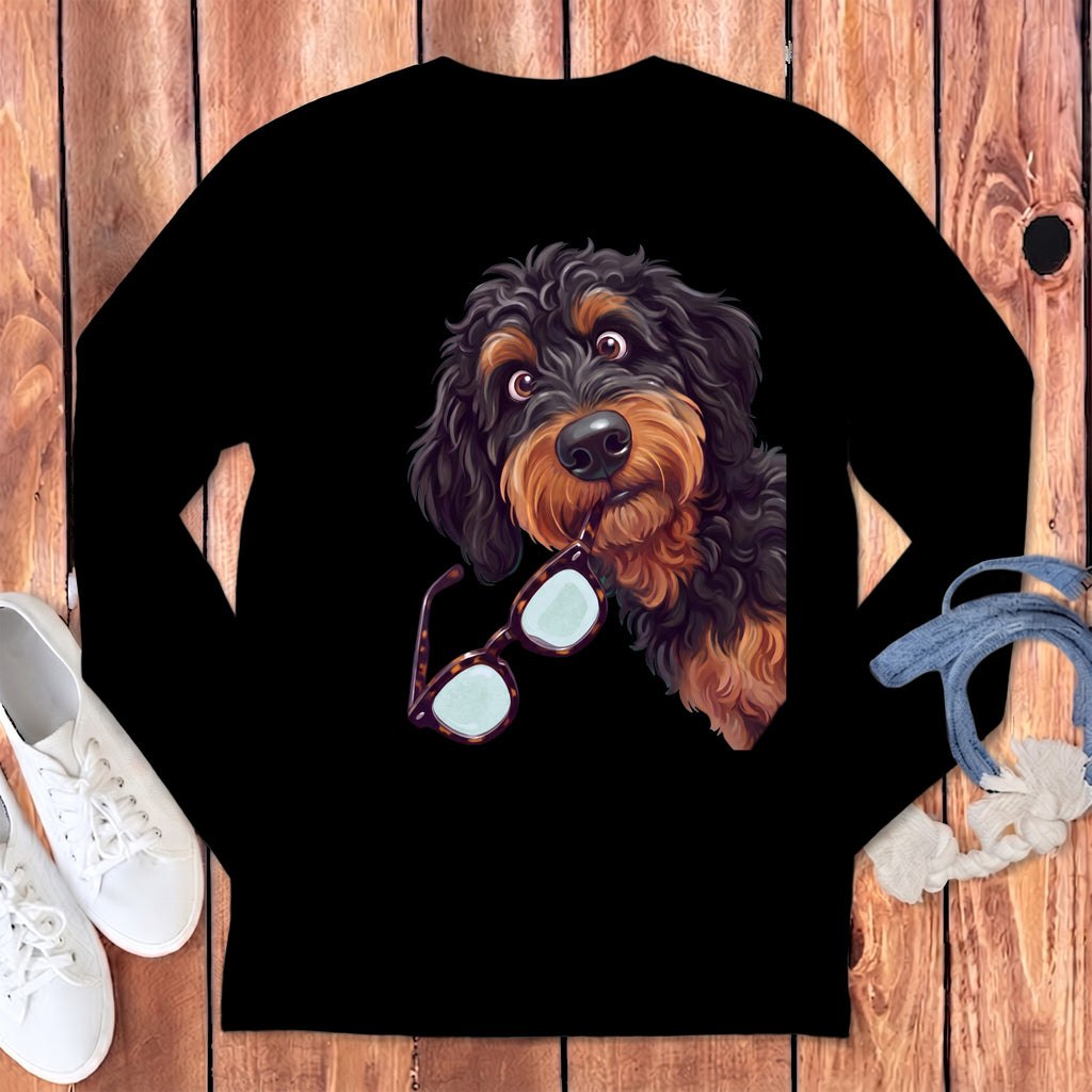 A black long-sleeve shirt featuring an illustration of a fluffy, black-and-tan dog holding glasses in its mouth.