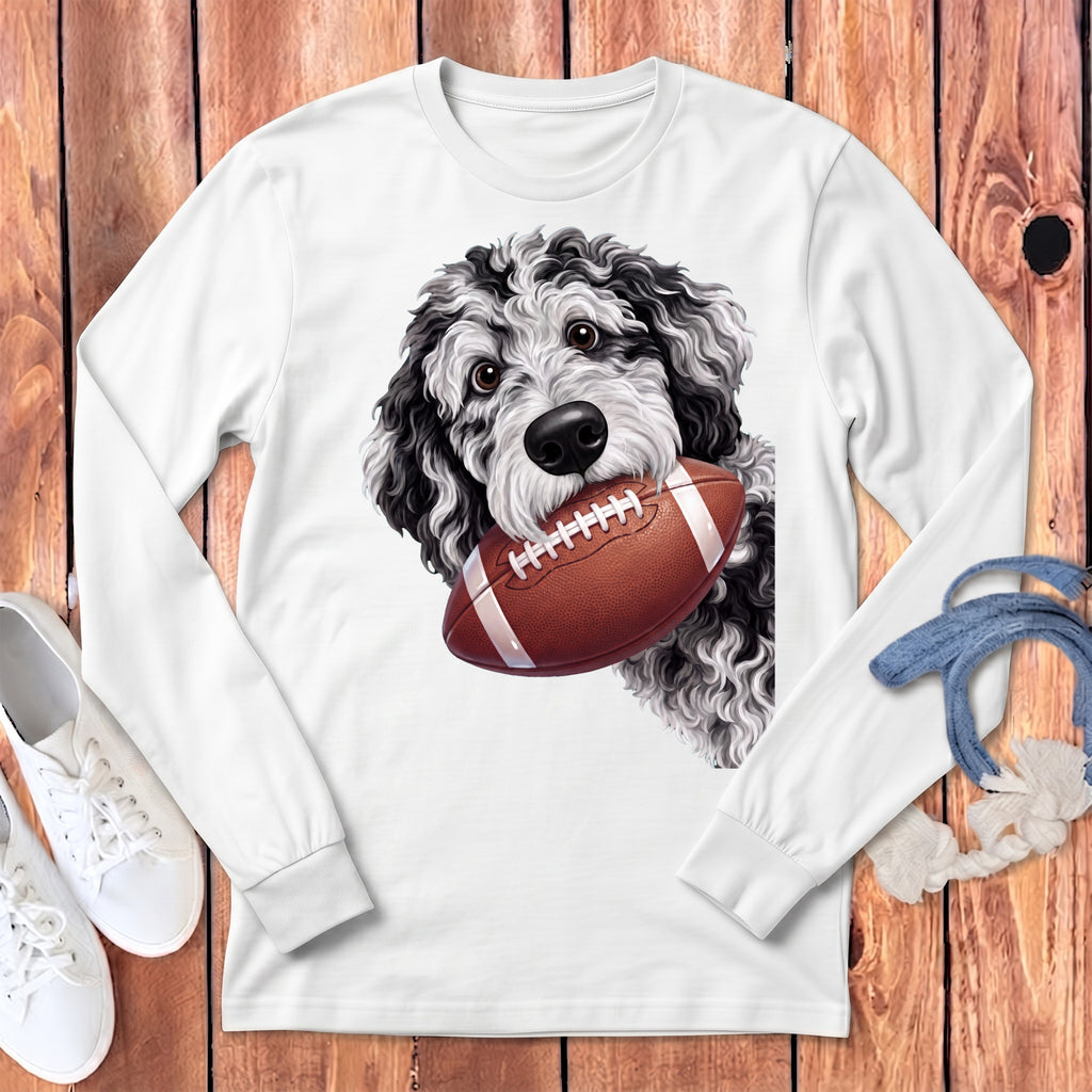 White long-sleeve shirt with a black and white doodle dog holding a football in its mouth.