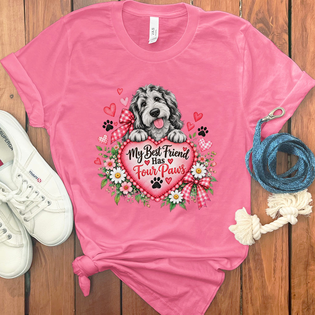 A pink t-shirt featuring a dog graphic, flowers, hearts, and the text My Best Friend Has Four Paws.