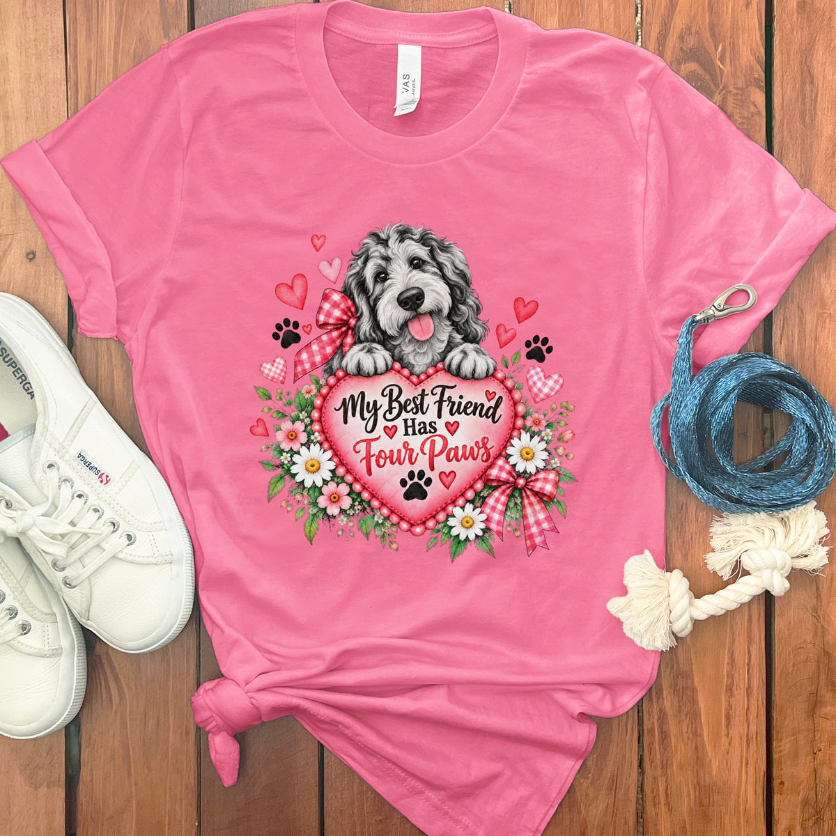 A pink t-shirt featuring a dog graphic, flowers, hearts, and the text My Best Friend Has Four Paws.