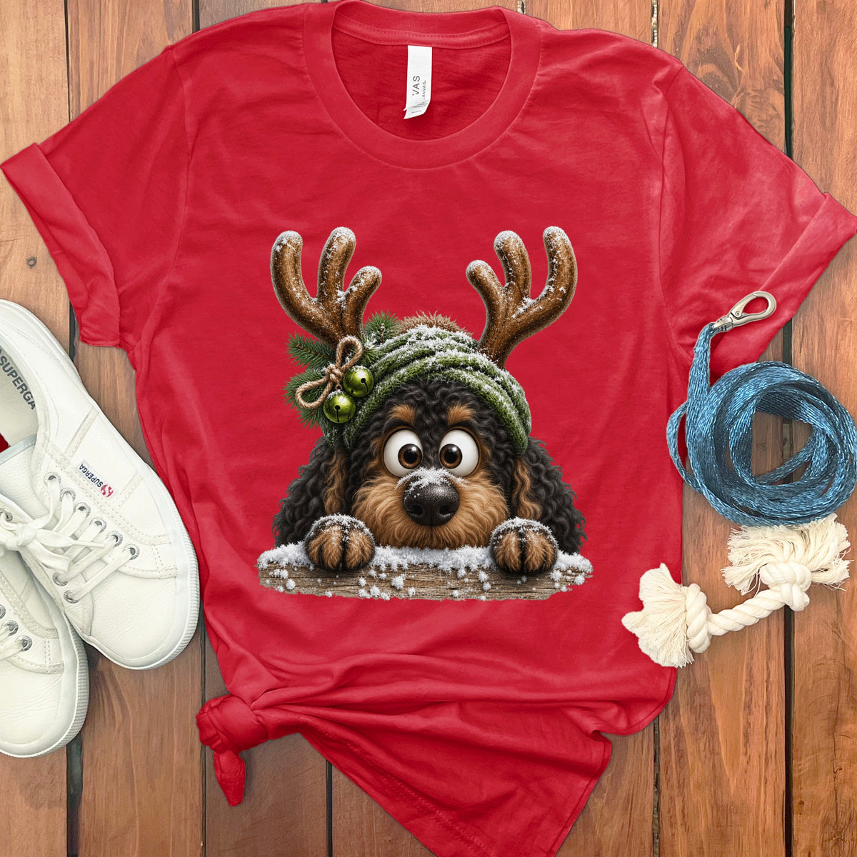 Red t-shirt with a cartoon dog wearing antlers and a hat, peeking over wood.