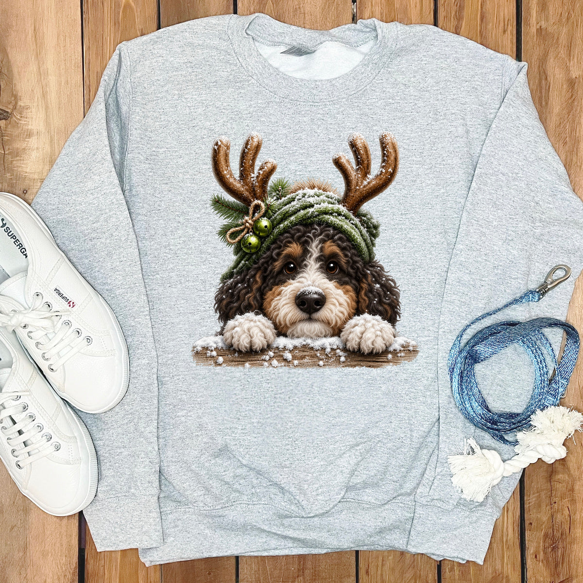 Grey sweatshirt with a Bernedoodle dog wearing reindeer antlers and a snowy hat.