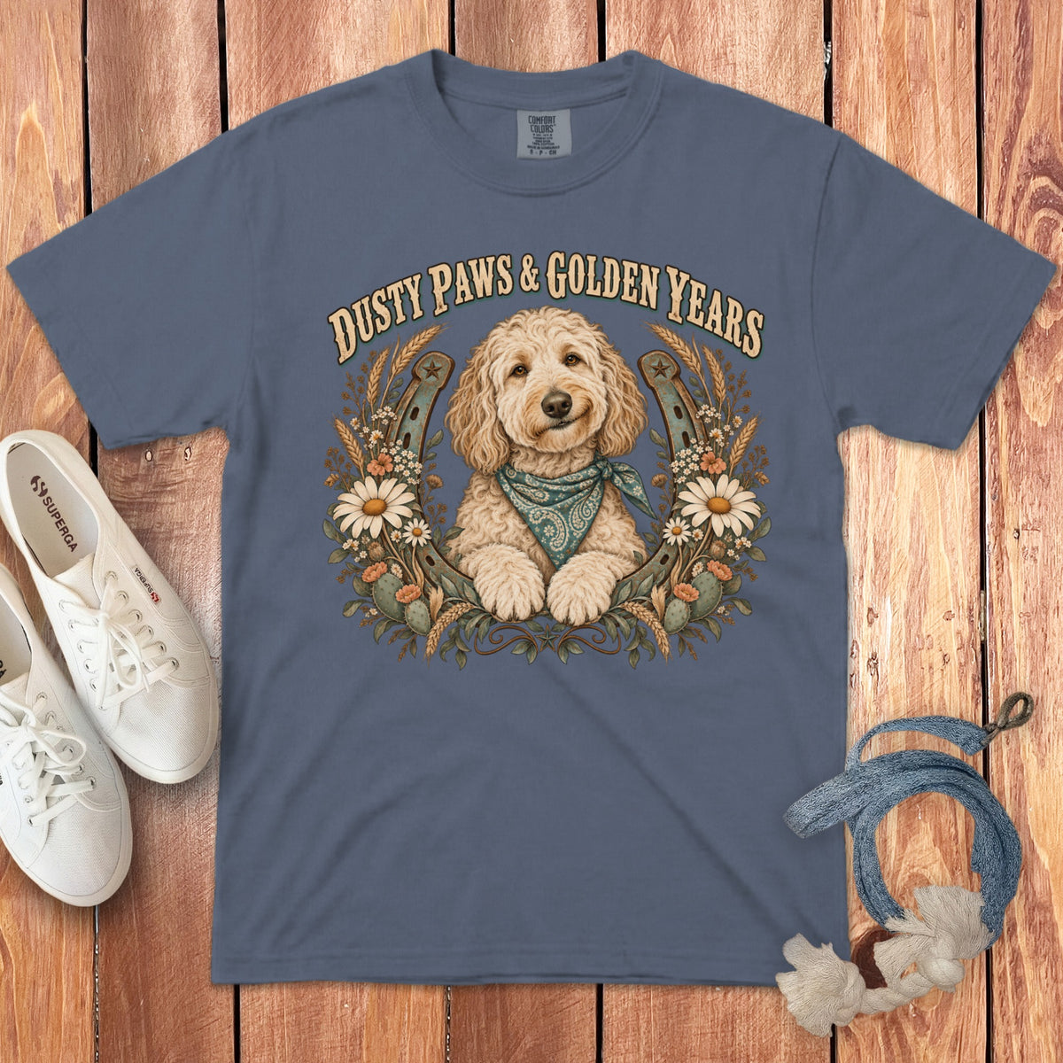 A slate-blue t-shirt featuring a doodle dog graphic, horseshoes, flowers, and the text Dusty Paws and Golden Years.