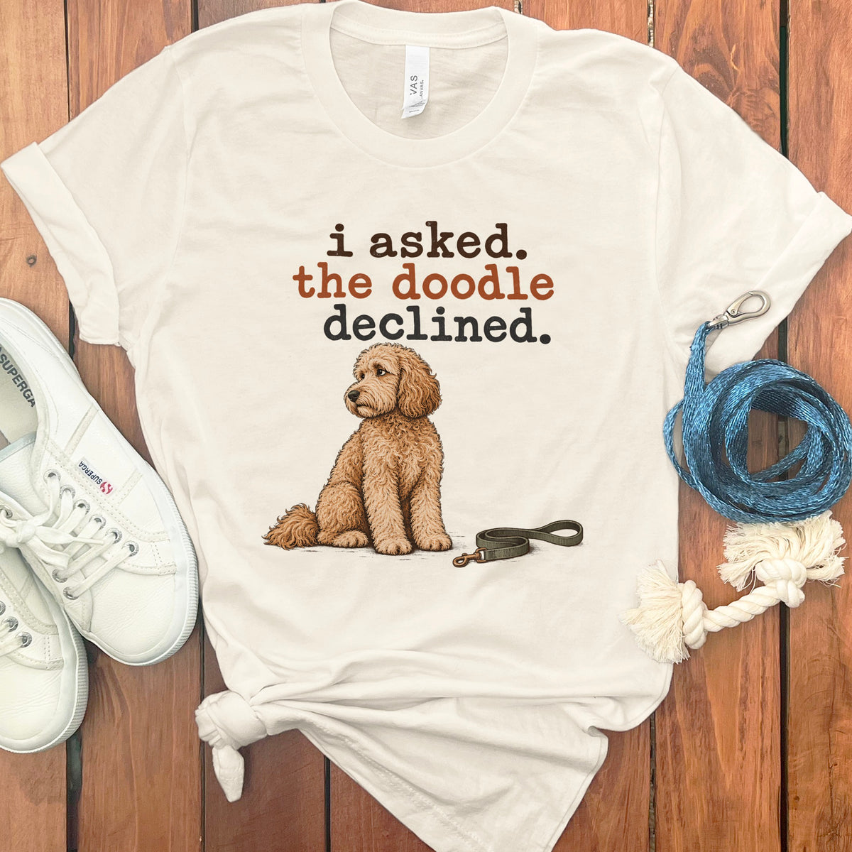 White t-shirt with brown text "i asked. the doodle declined." and a doodle dog illustration.