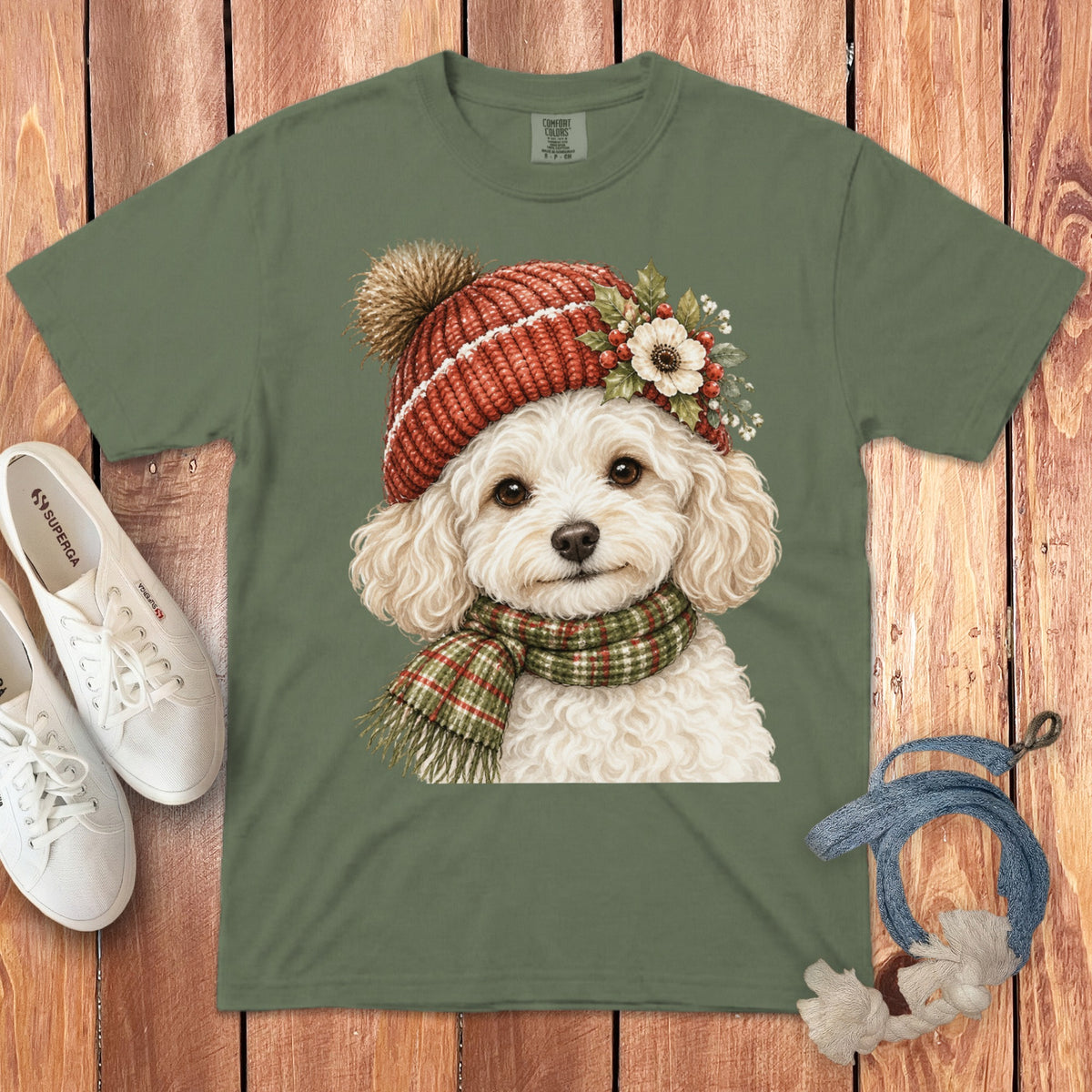 Green t-shirt with illustration of a white poodle wearing a red knitted hat and scarf.