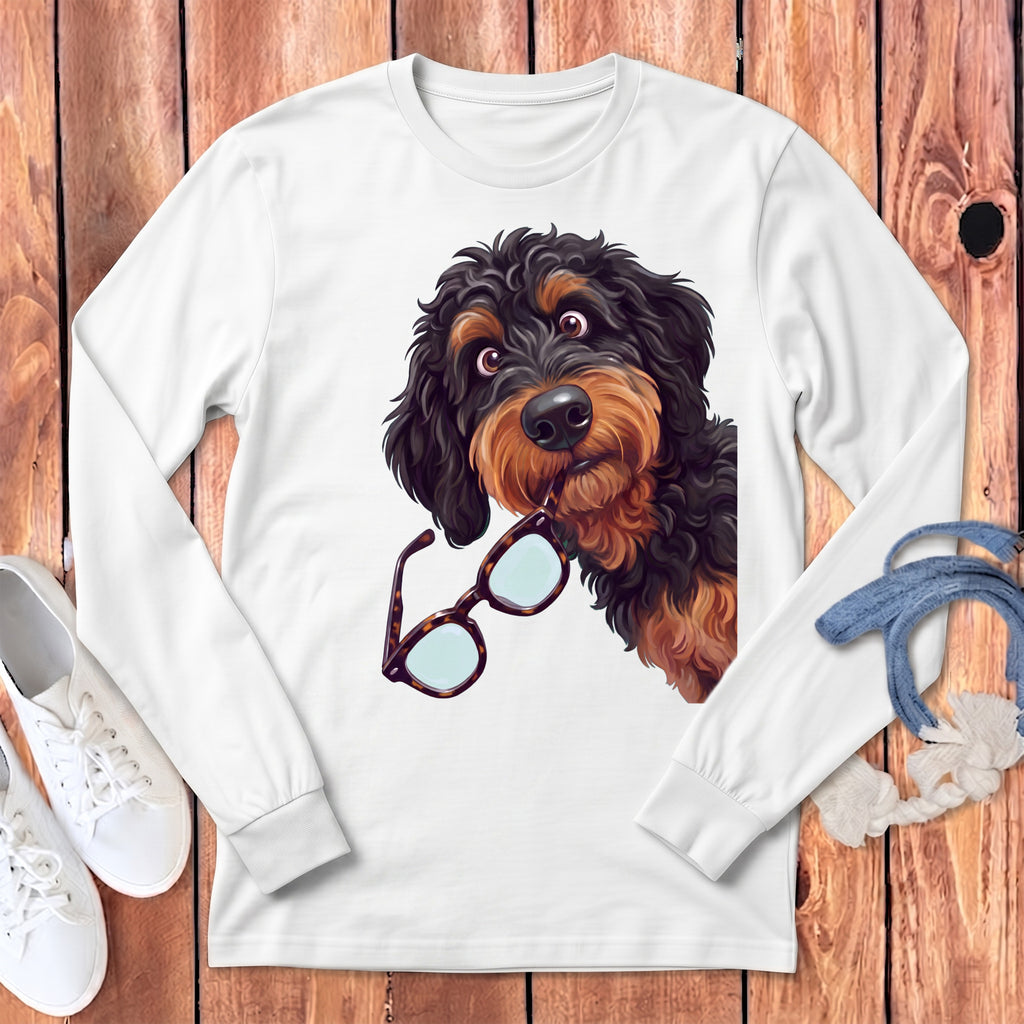 White long-sleeve t-shirt featuring a graphic of a black and brown doodle dog holding glasses in its mouth.