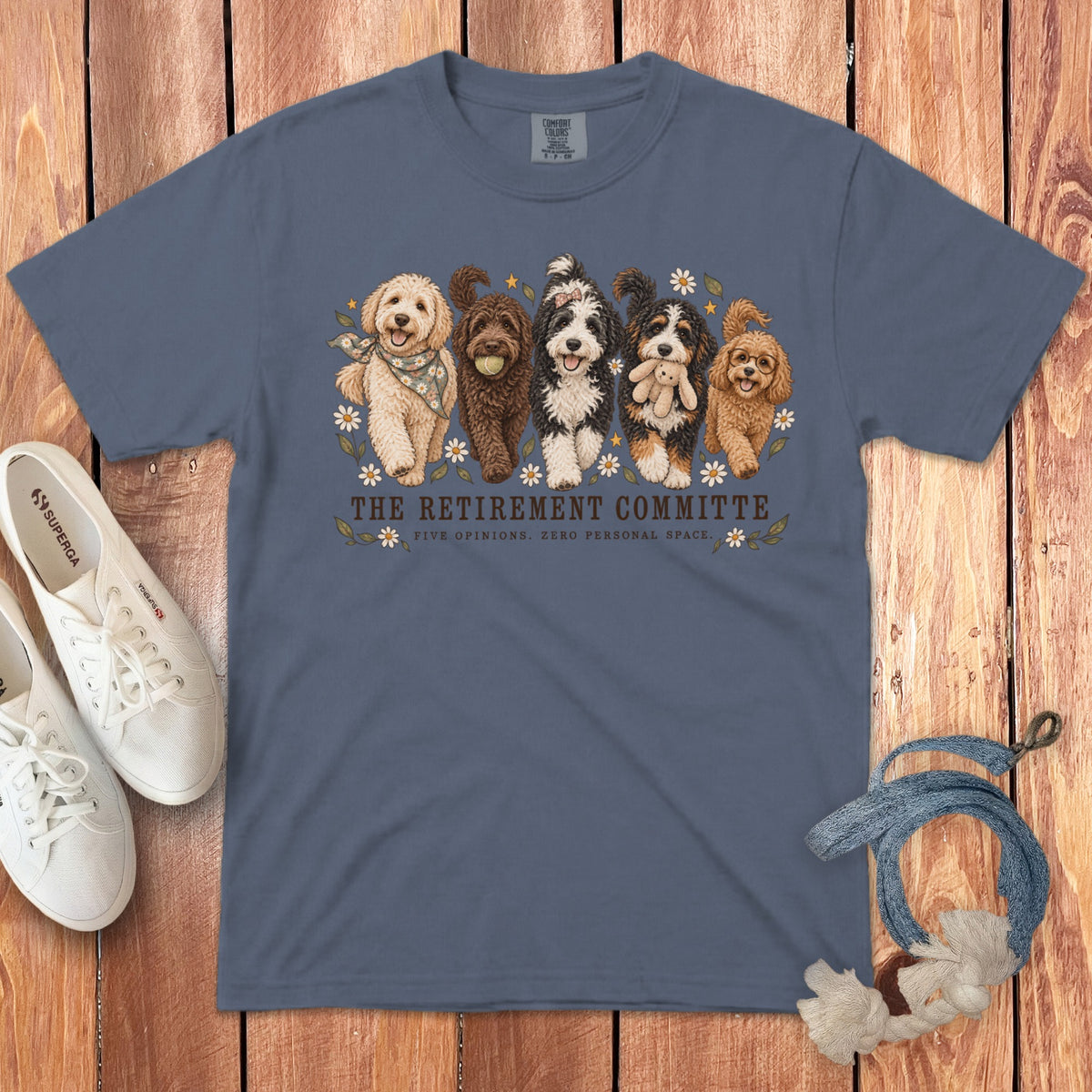 A blue t-shirt printed with five dogs and text reading "THE RETIREMENT COMMITTEE" and "FIVE OPINIONS. ZERO PERSONAL SPACE."