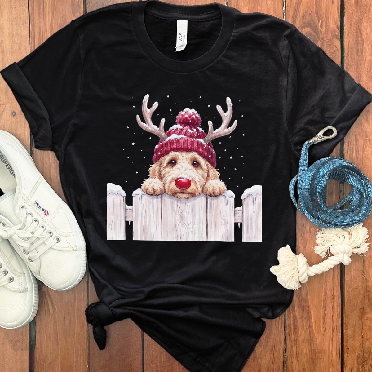 Black t-shirt with a doodle dog wearing a red beanie and reindeer antlers.