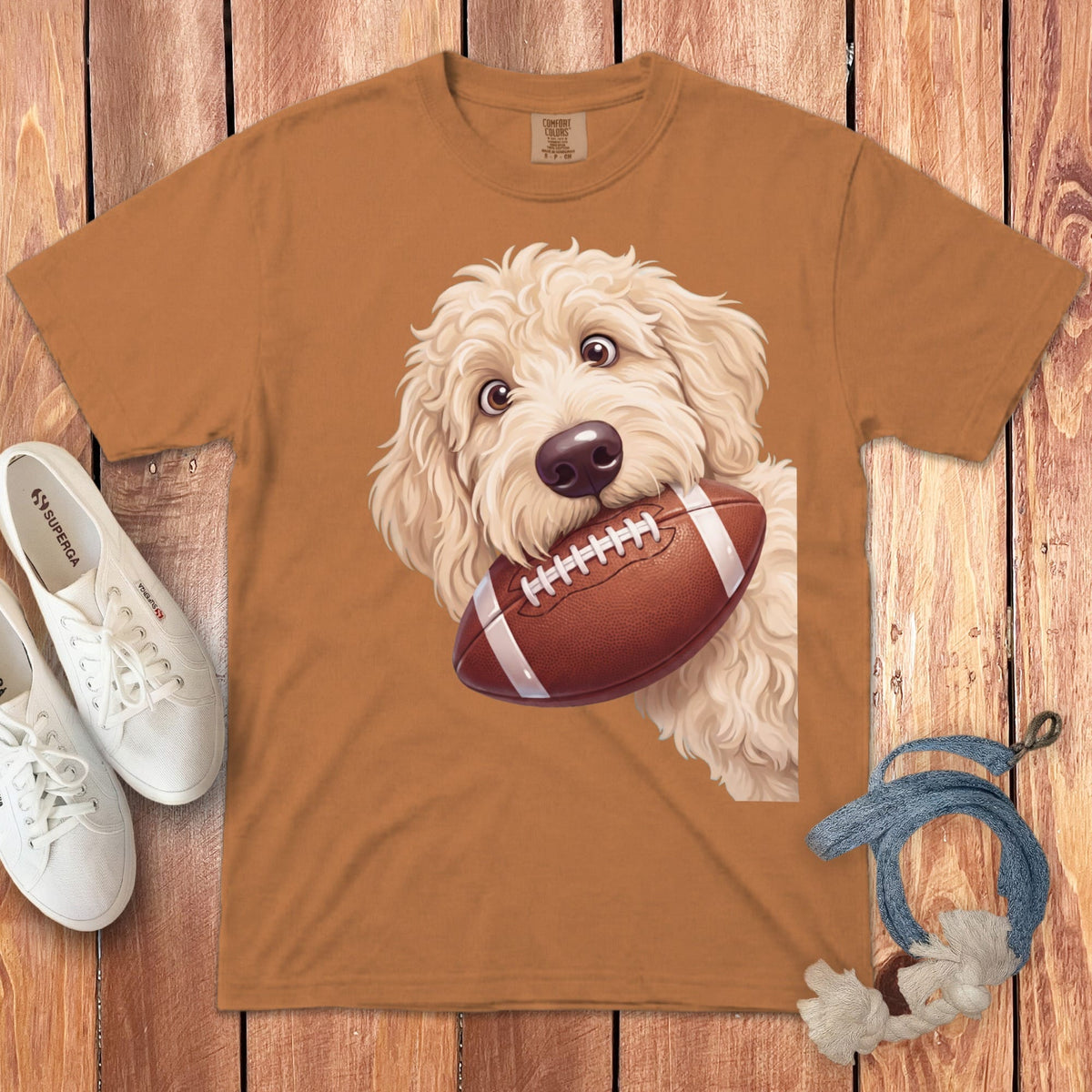 Brown t-shirt with a doodle dog graphic holding a football.