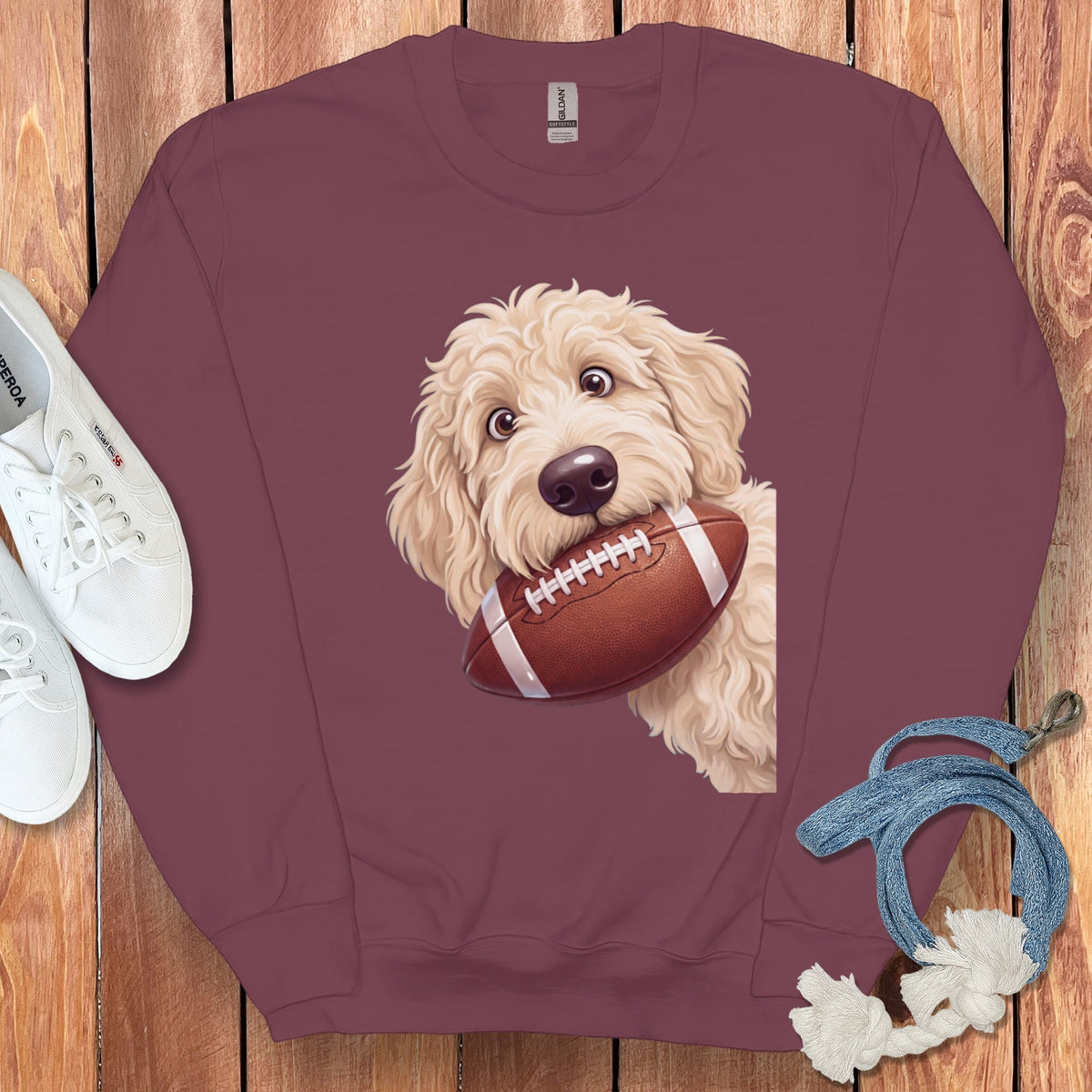 Maroon sweatshirt with a drawing of a goldendoodle holding a football.