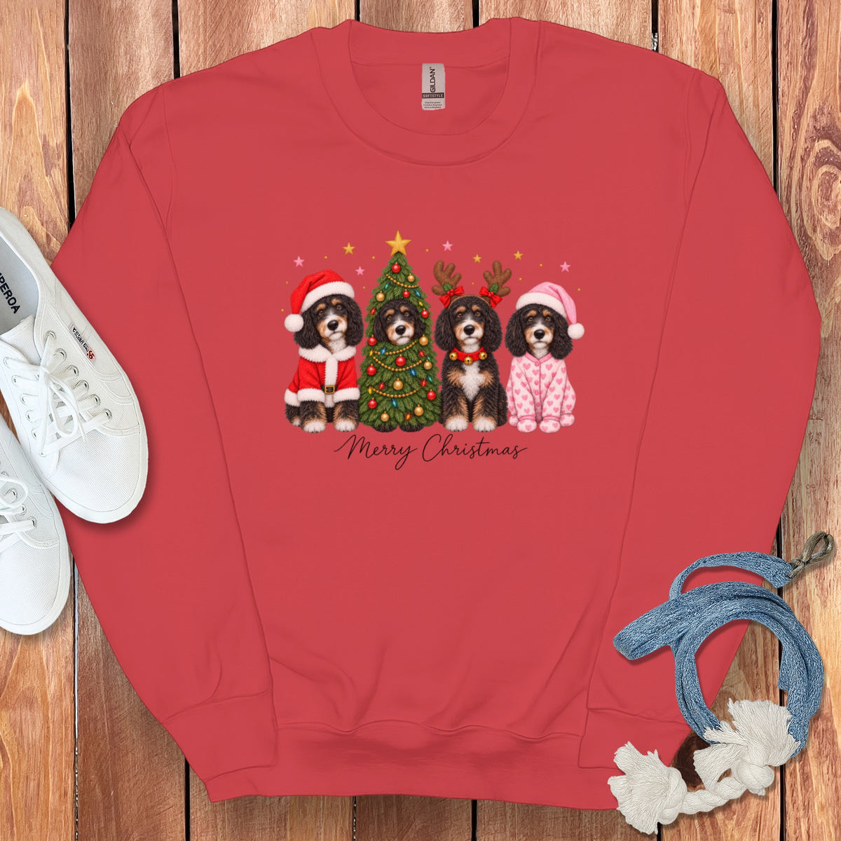 Red crewneck sweatshirt featuring a graphic of four Bernedoodles in Christmas attire surrounding a decorated tree.