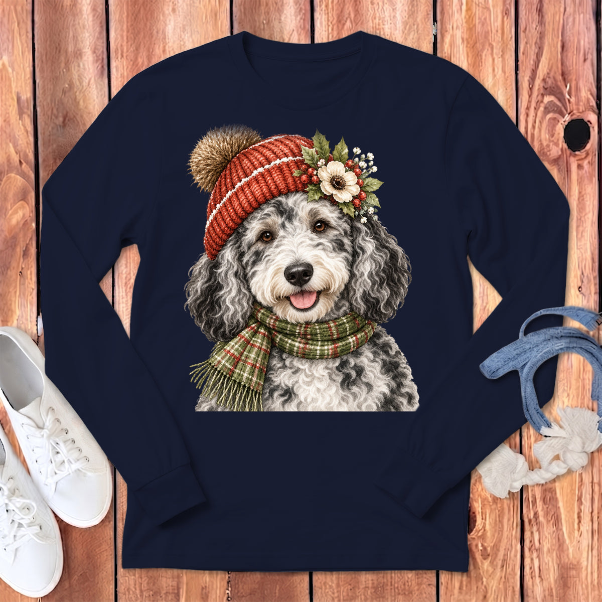 Doodle dog wearing winter hat and scarf on navy long sleeve shirt.