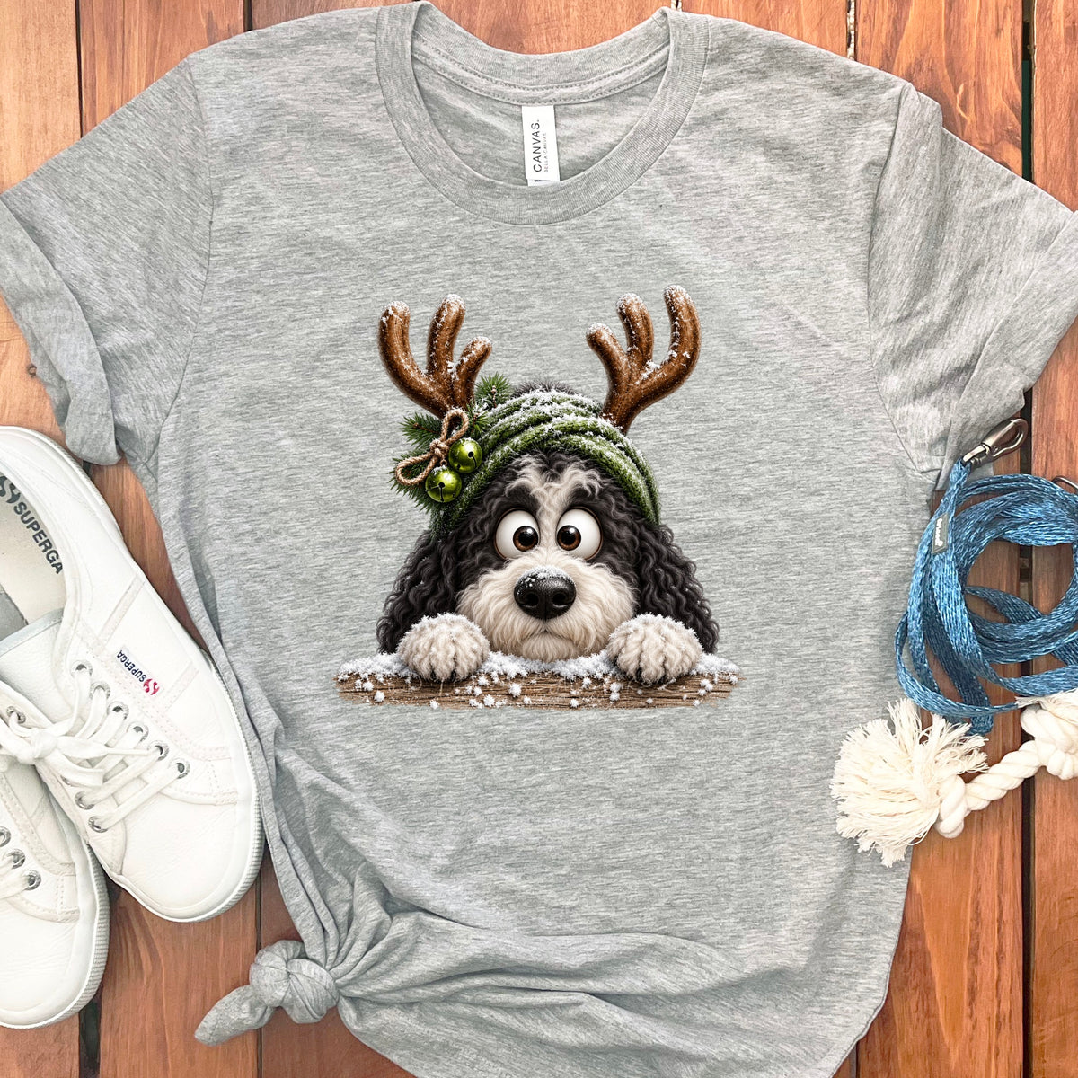 Grey t-shirt with a cartoon Bernedoodle wearing reindeer antlers and a knit hat.