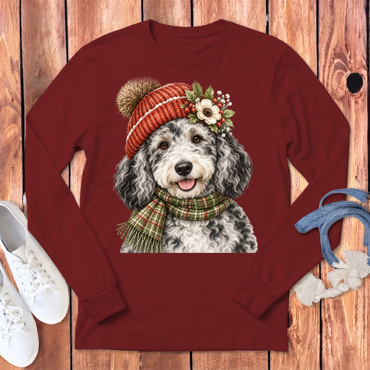 Bernedoodle dog wearing a knit hat and plaid scarf with floral accents.