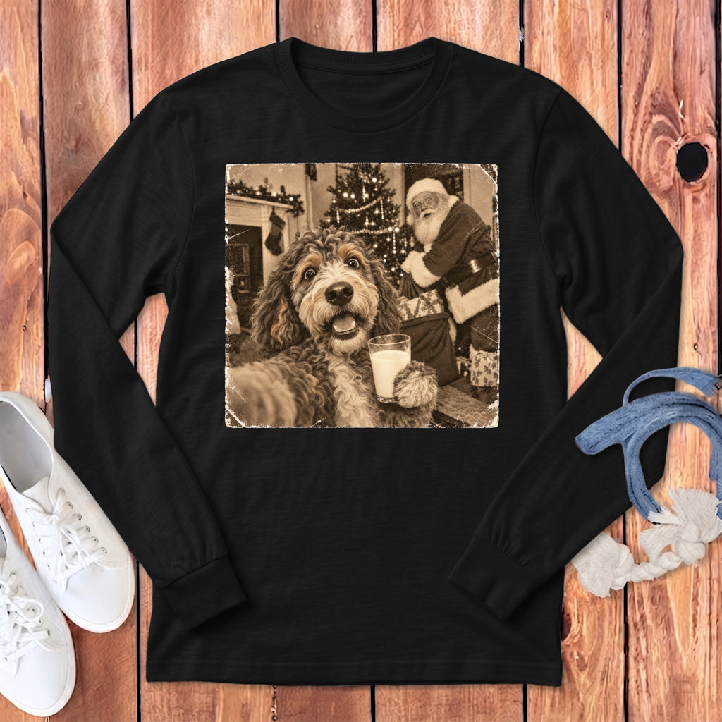 A black long-sleeve t-shirt features a graphic print of a dog holding a glass of milk with Santa Claus in the background.