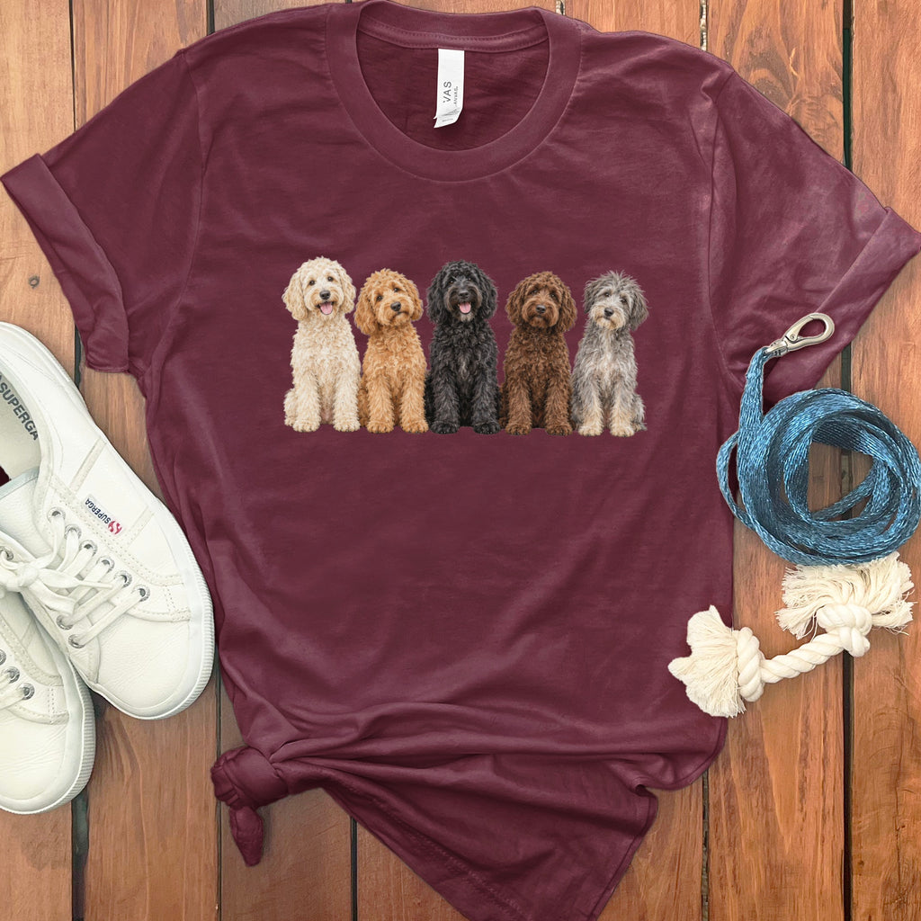 Maroon t-shirt with a graphic of five different colored doodle dogs sitting.