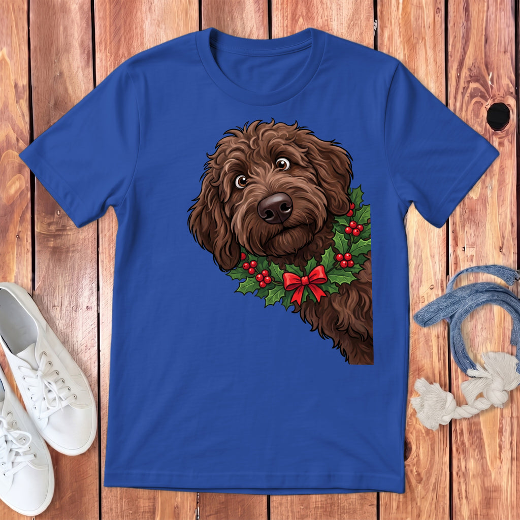 Brown doodle dog wearing a Christmas holly wreath with red bow on blue shirt.