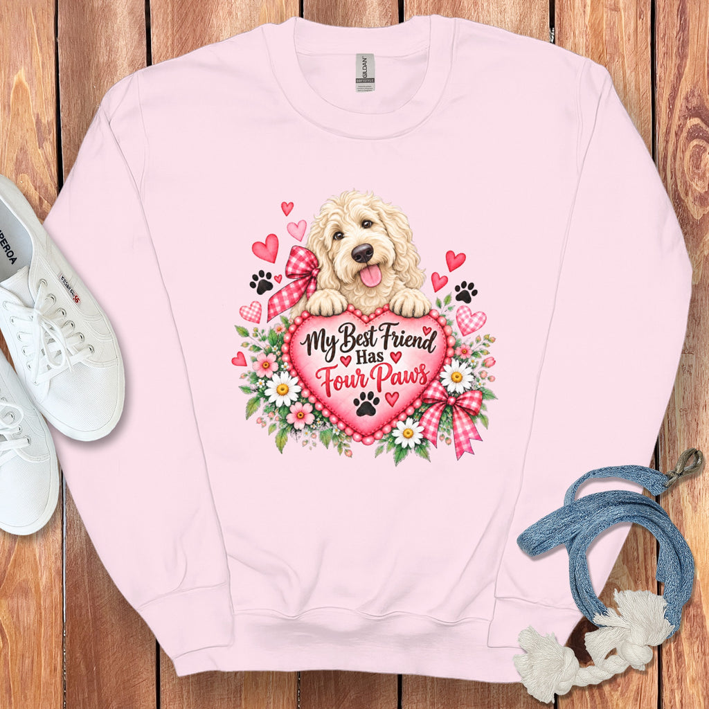 Light pink crewneck sweatshirt featuring a graphic of a golden puppy resting on a heart with text reading My Best Friend Has Four Paws.