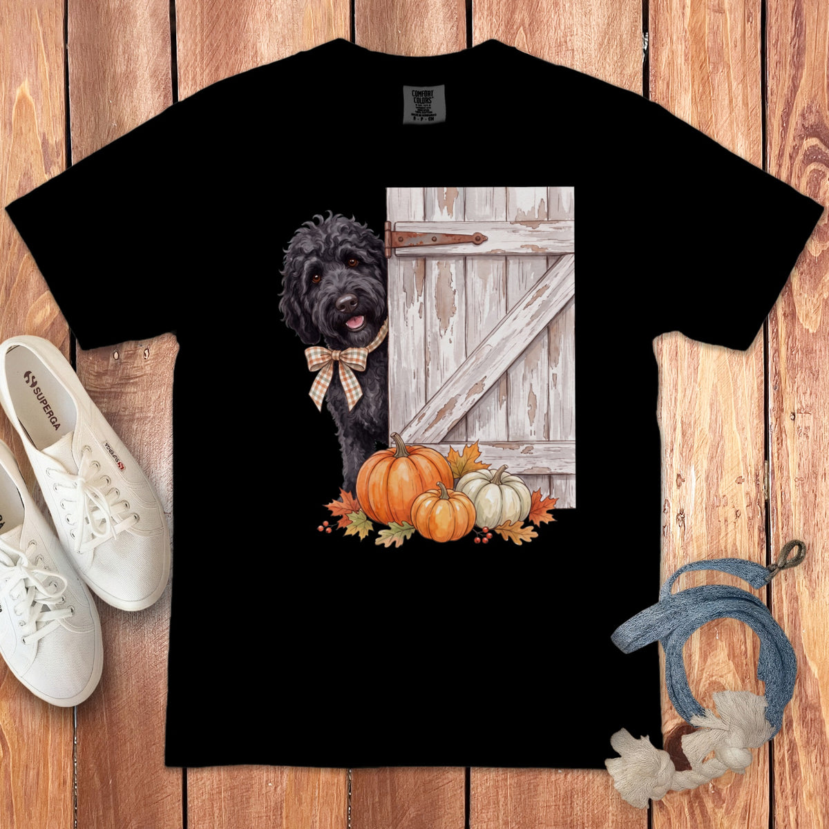Black t-shirt with a black dog peeking from behind a barn door with pumpkins.