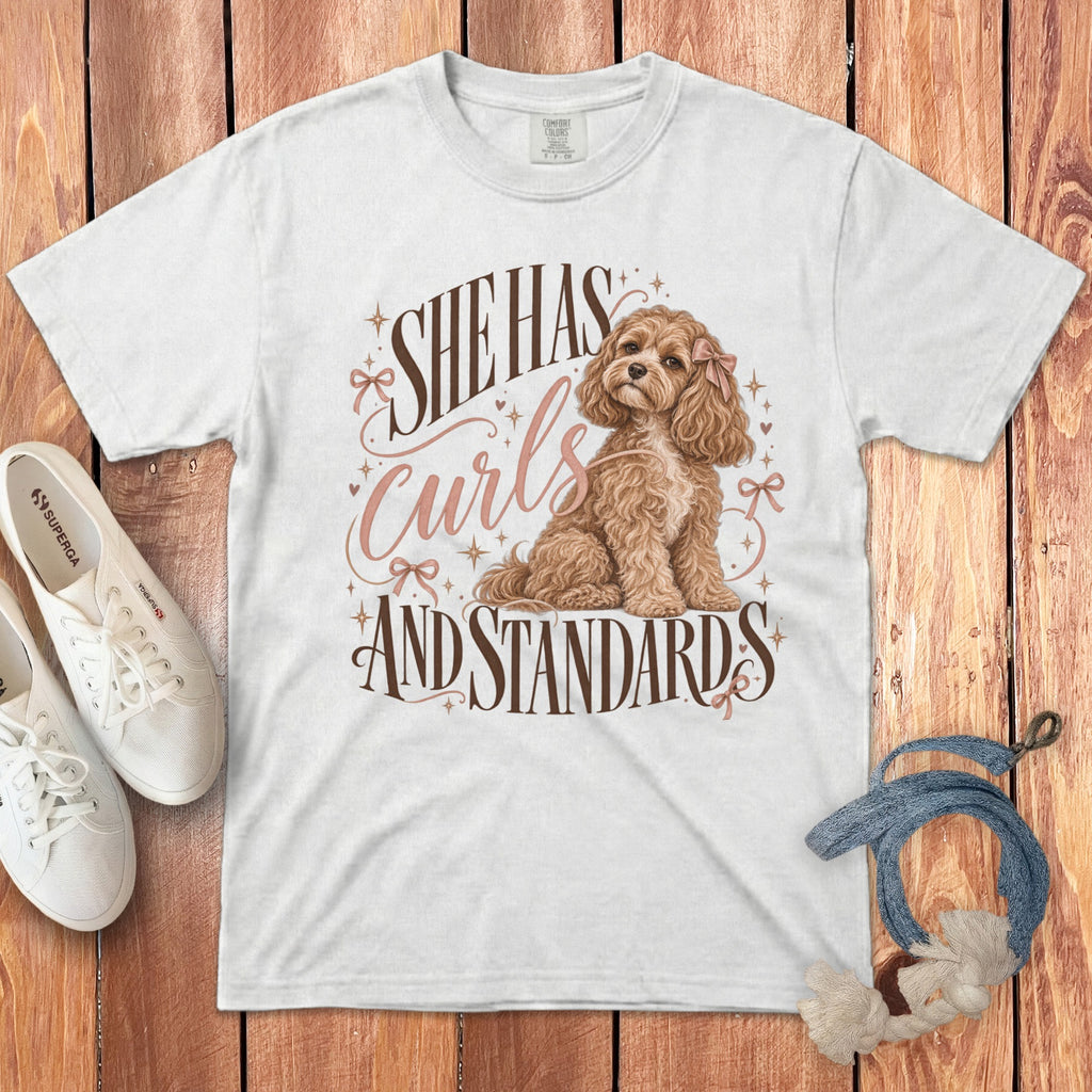 A white crewneck t-shirt featuring a graphic of a curly brown dog and the text She Has Curls and Standards.