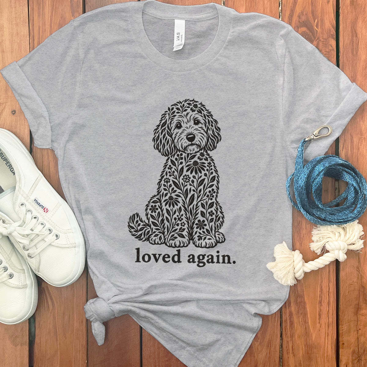 Grey t-shirt with a black floral dog graphic and text "loved again."