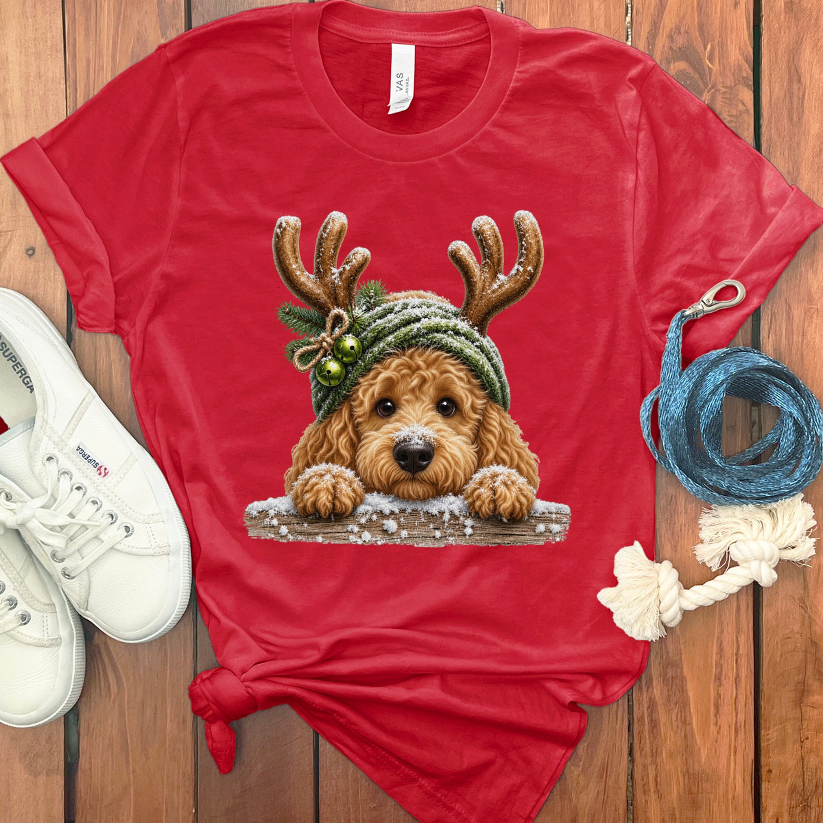Red t-shirt with a doodle dog wearing antlers and a knitted hat, dusted with snow.