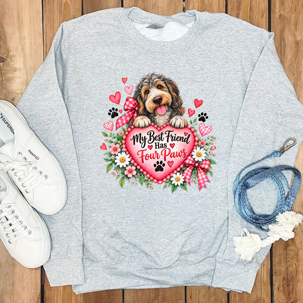 Light gray crewneck sweatshirt featuring a doodle dog graphic, pink heart, floral details, and text reading "My Best Friend Has Four Paws".