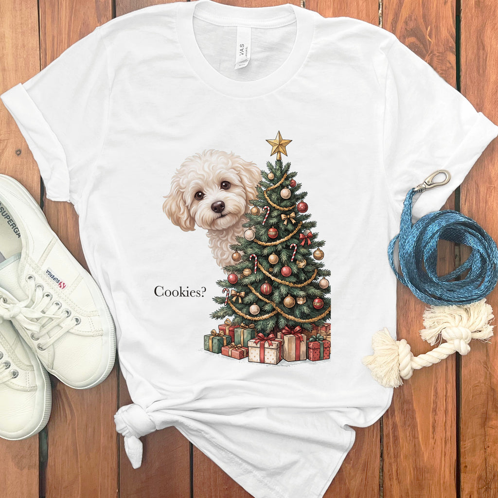 White t-shirt with white dog peeking from behind a decorated Christmas tree and presents. Text reads "Cookies?".