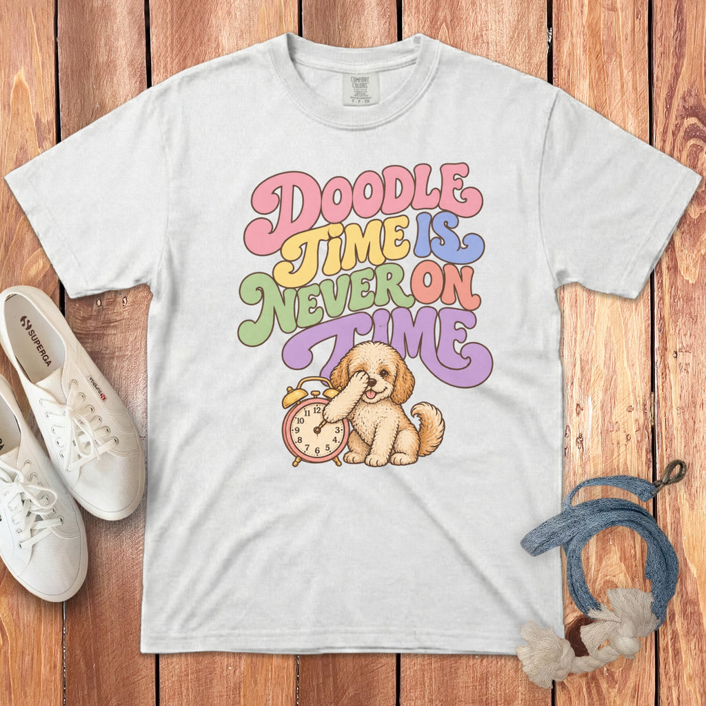 A white t-shirt featuring a cartoon doodle dog covering its eyes next to an alarm clock, with the text Doodle Time Is Never On Time.
