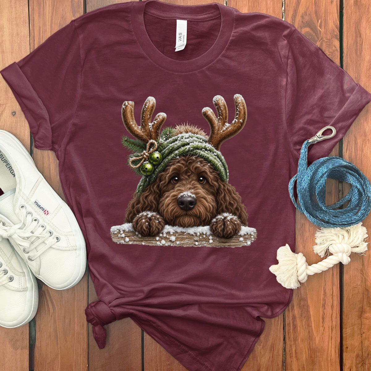 Maroon t-shirt with a doodle dog wearing a knit hat with antlers and bells.
