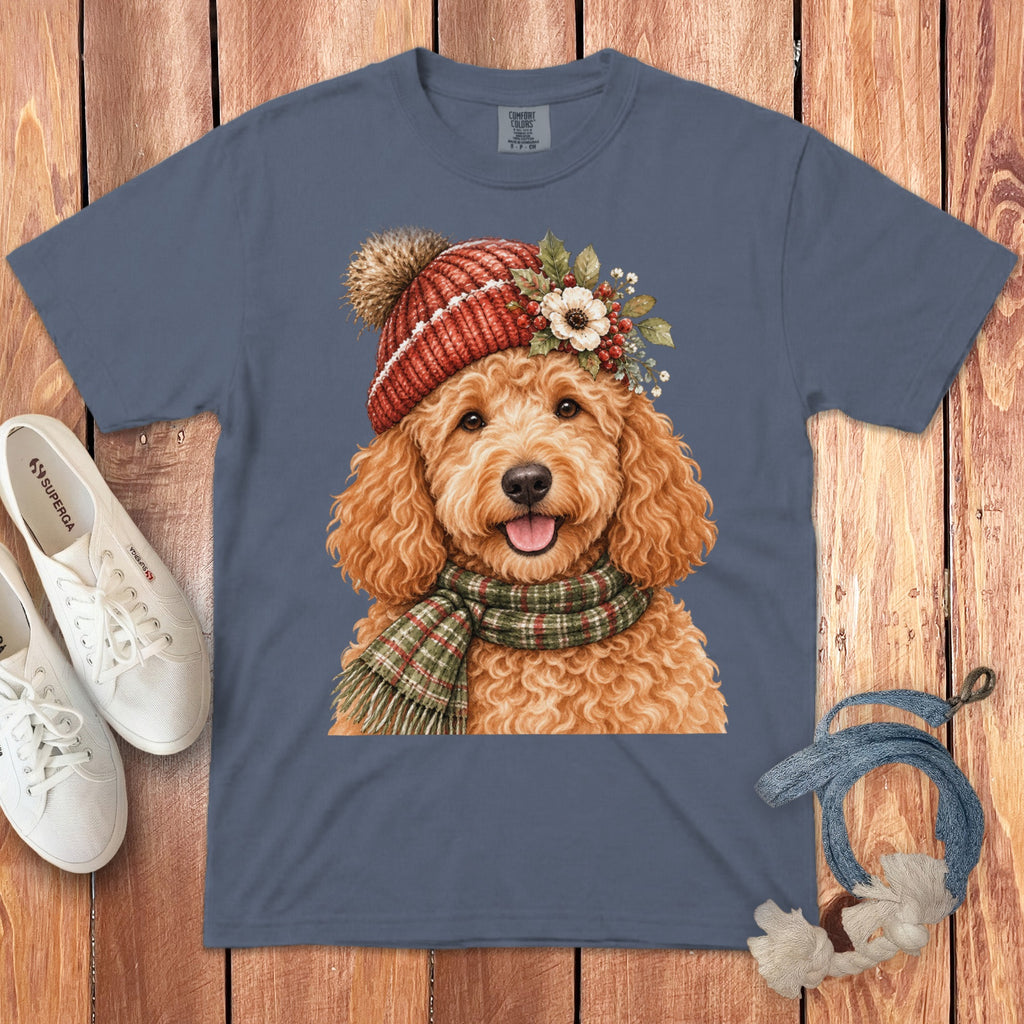 Watercolor goldendoodle wearing a red beanie and green scarf on a blue t-shirt.