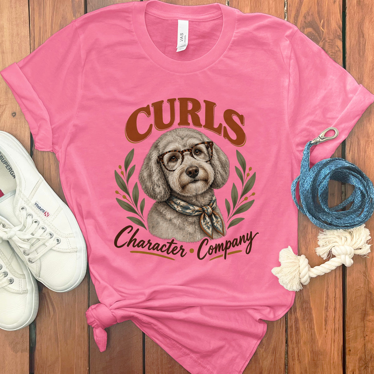Pink t-shirt with dog graphic, glasses, scarf, and text "CURLS Character Company".
