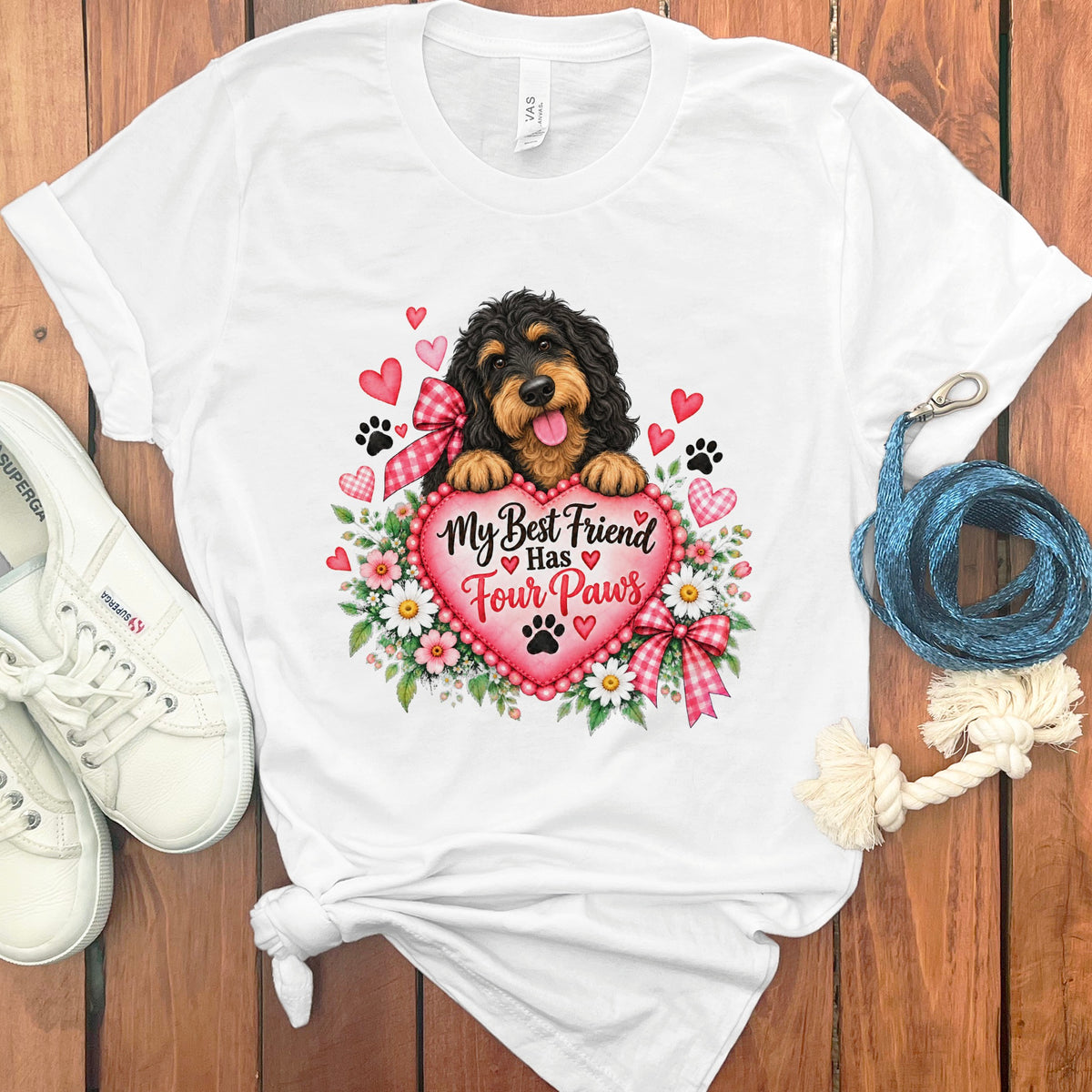 A white t-shirt featuring a doodle dog holding a pink heart with the text "My Best Friend Has Four Paws."