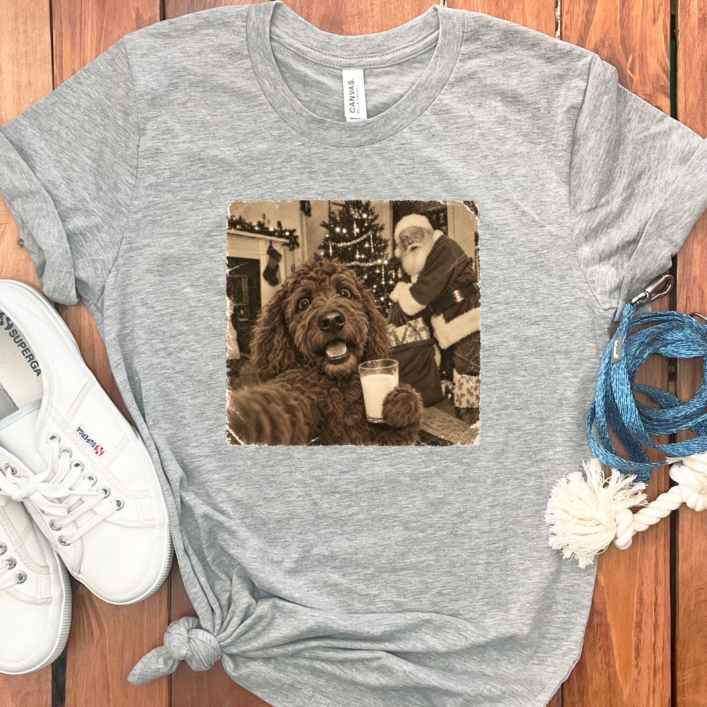 A gray t-shirt featuring a sepia image of a brown dog holding a glass of milk with Santa Claus in the background.