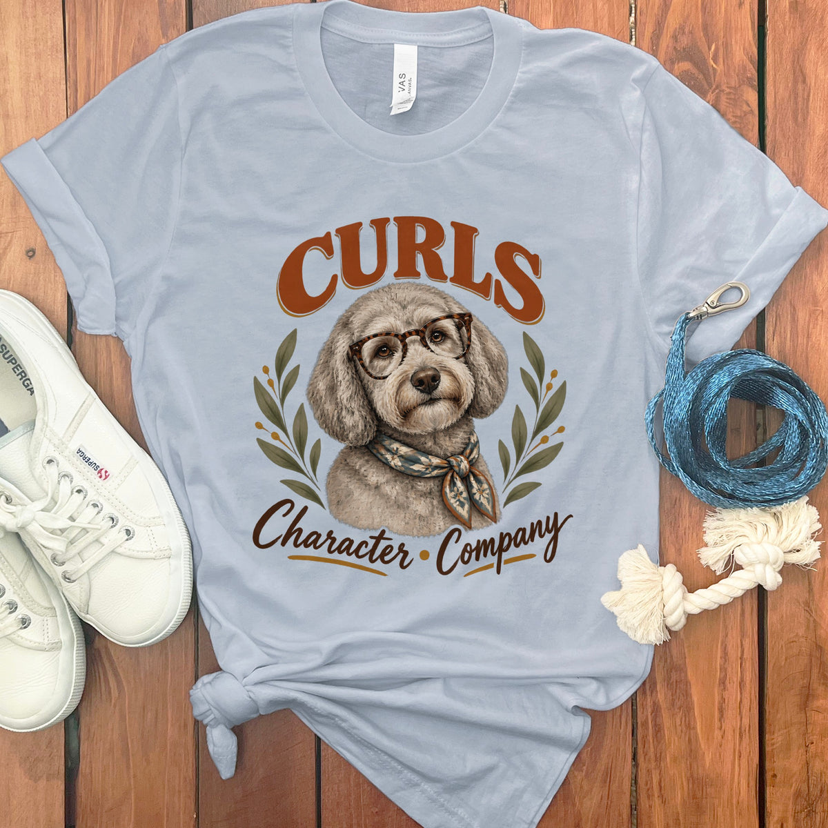 Light blue t-shirt with a dog wearing glasses and scarf. Text reads "Curls Character Company".
