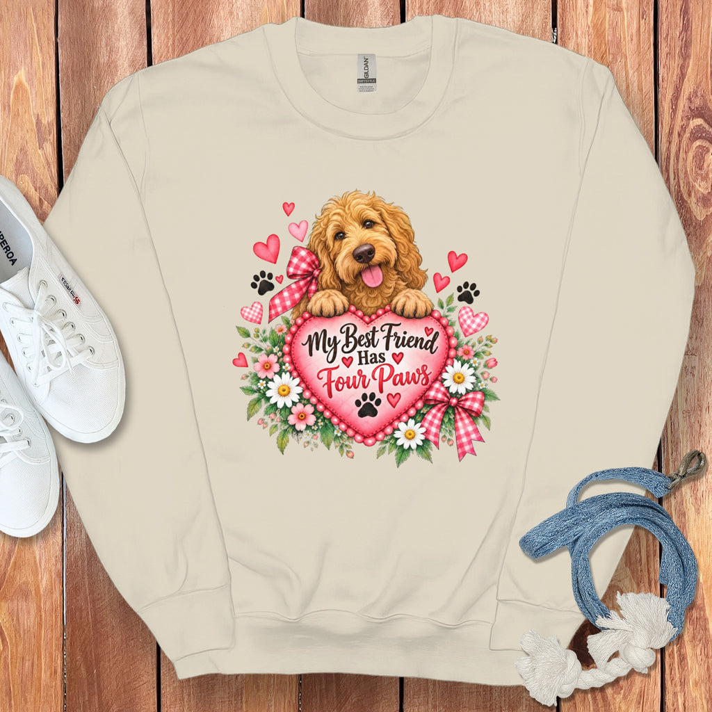 Beige crewneck sweatshirt with a graphic of a golden doodle resting on a pink heart surrounded by hearts, flowers, and the text My Best Friend Has Four Paws.