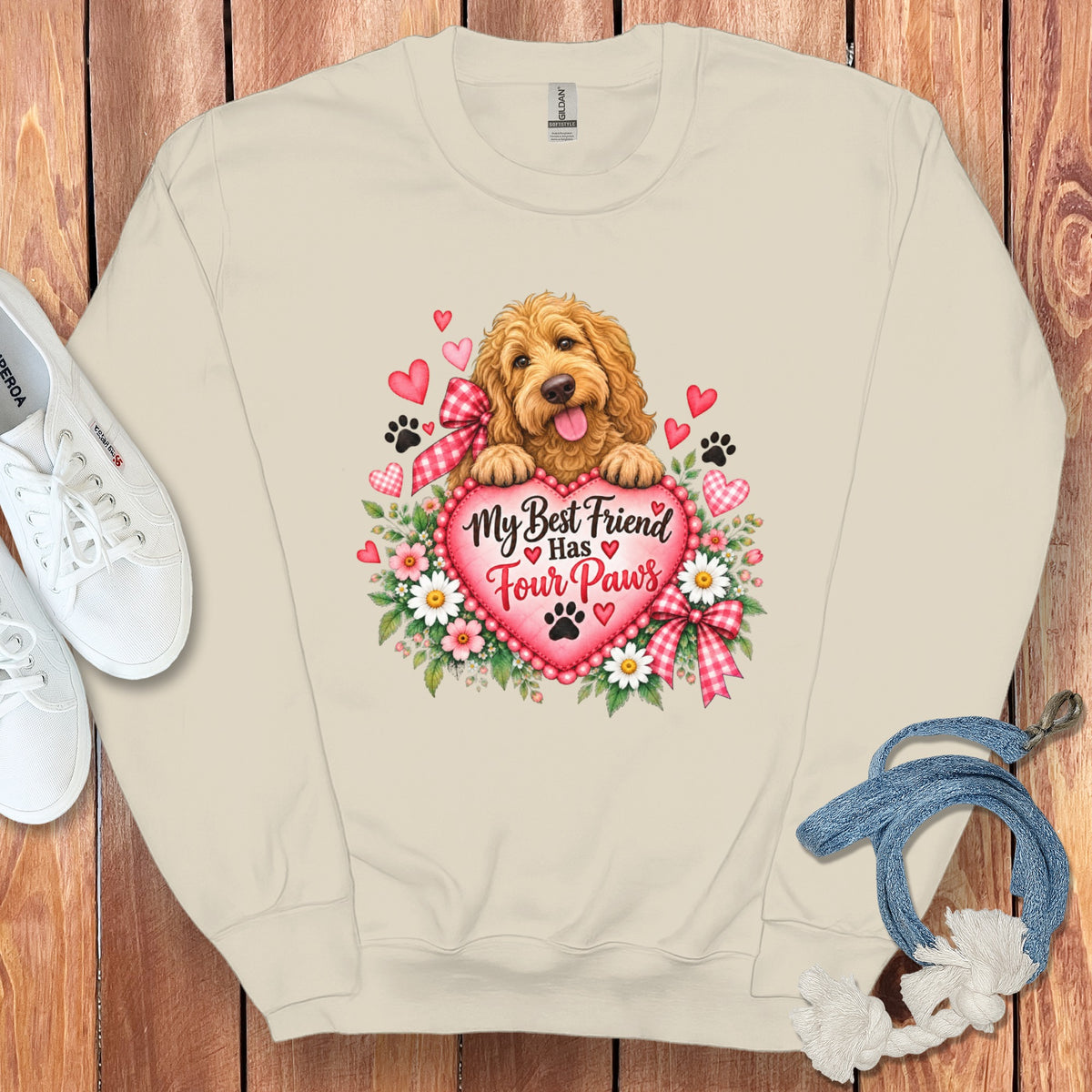 Beige crewneck sweatshirt with a graphic of a golden doodle resting on a pink heart surrounded by hearts, flowers, and the text My Best Friend Has Four Paws.