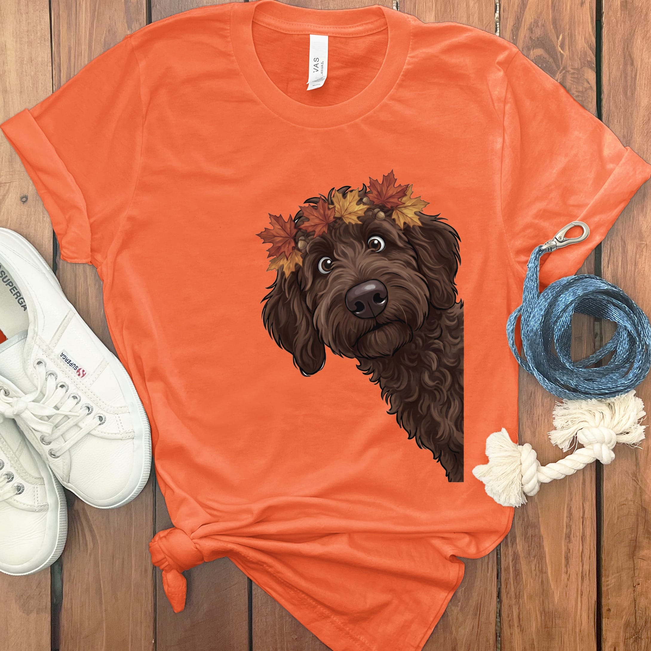 Orange t-shirt featuring a brown dog wearing a fall leaf crown.