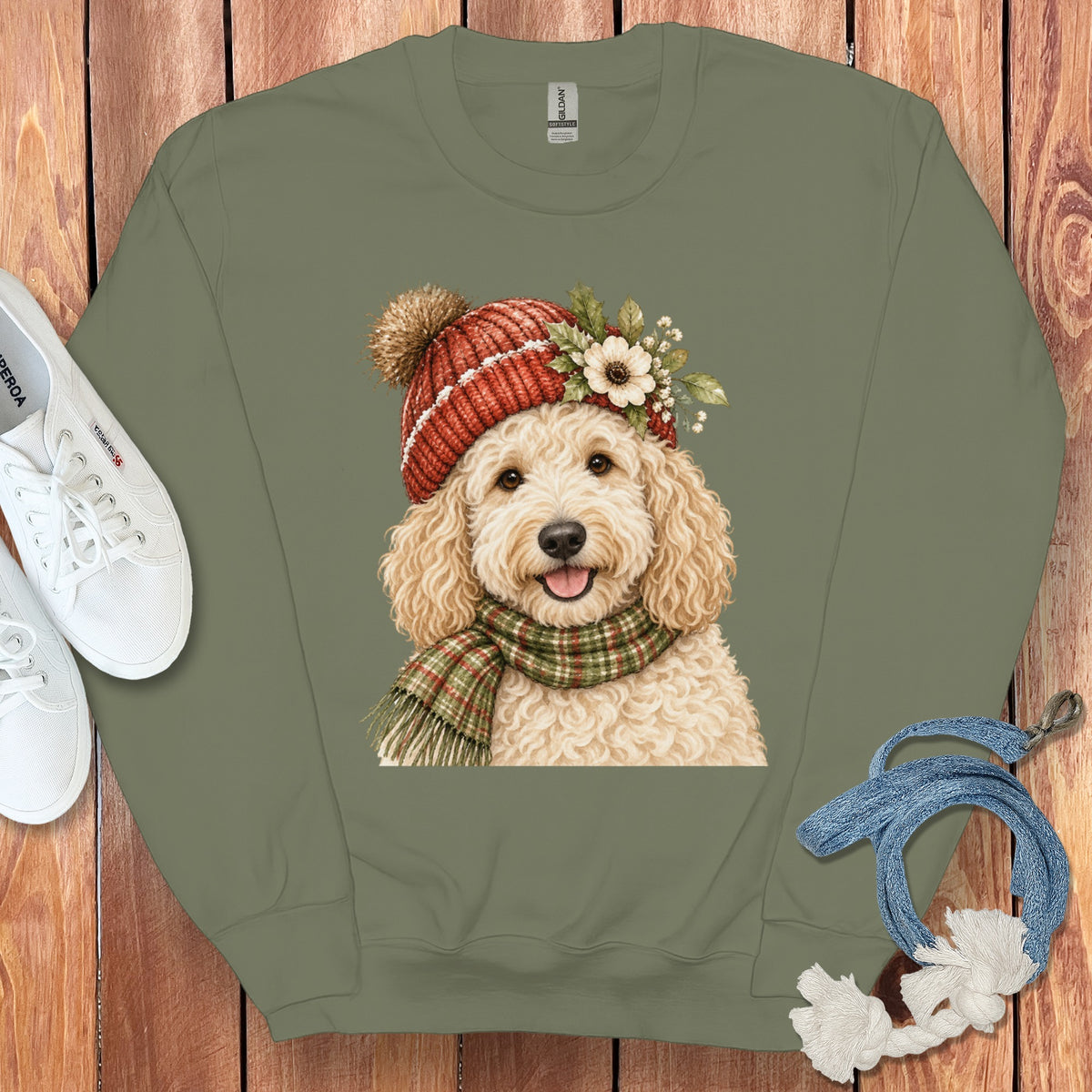 Crewneck sweatshirt with a cream doodle dog wearing a red knit hat and plaid scarf.