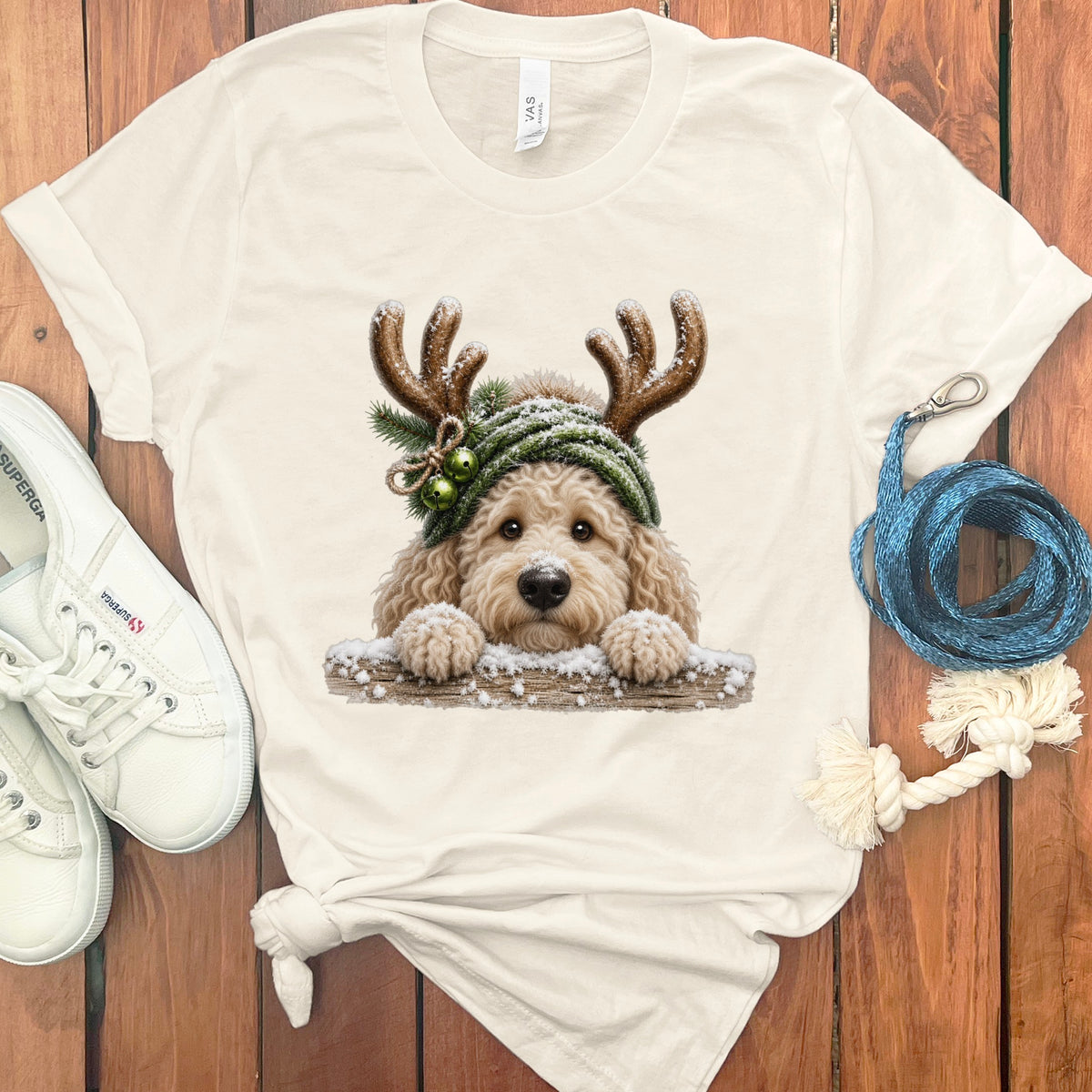 Cream t-shirt with a goldendoodle wearing reindeer antlers and a hat.
