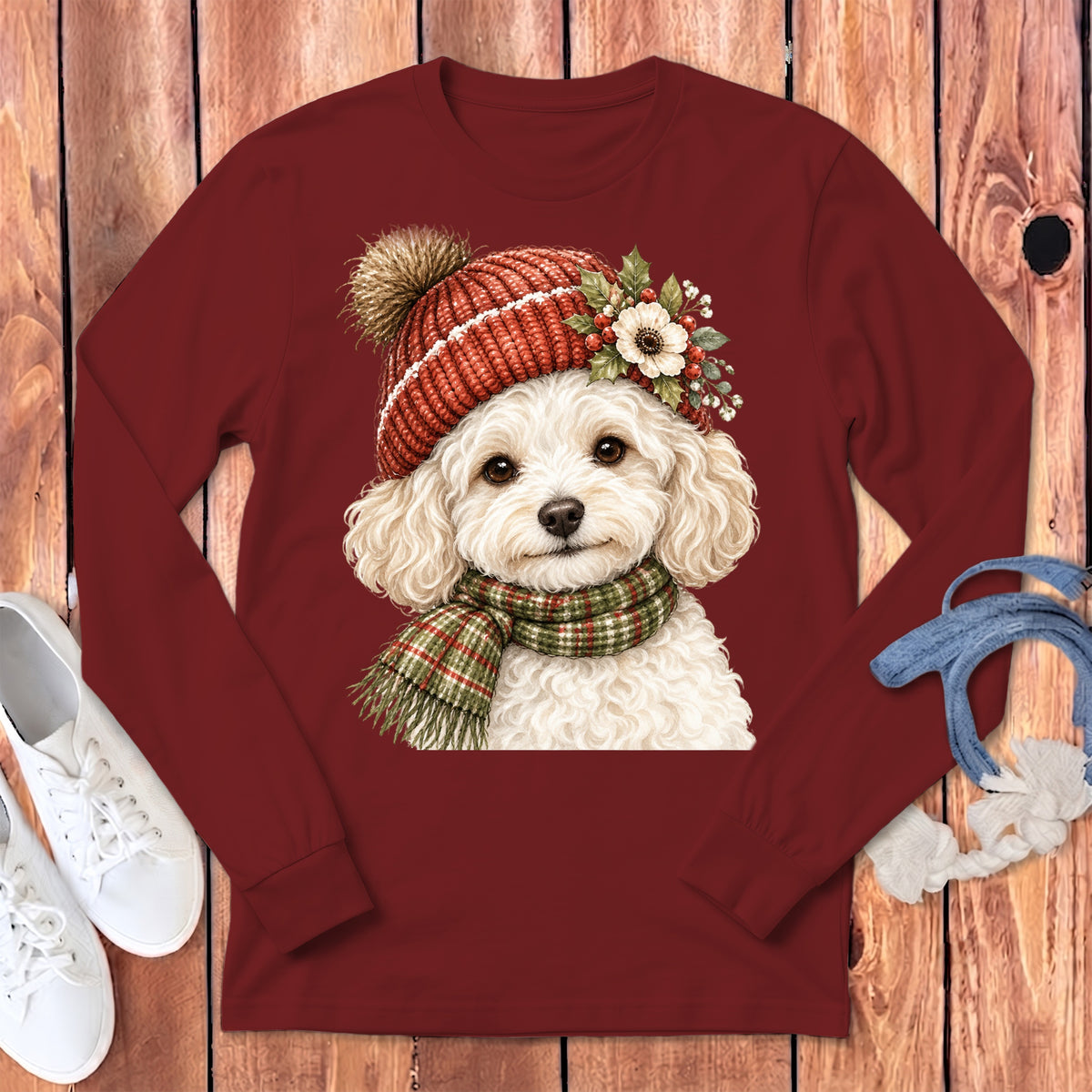 White poodle wearing a red knit hat and plaid scarf, printed on a maroon long-sleeve shirt.
