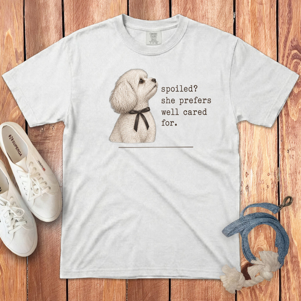 White t-shirt featuring an illustration of a fluffy white dog and the text spoiled? she prefers well cared for.