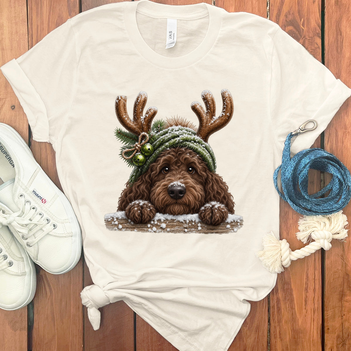 Cream t-shirt with illustration of a brown doodle dog wearing antlers and a winter hat.