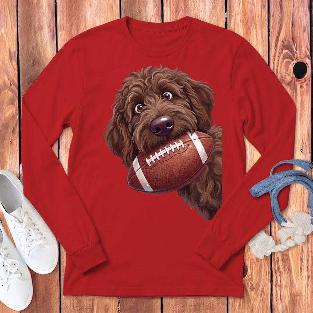Brown poodle with a football in its mouth on a red long-sleeved shirt.