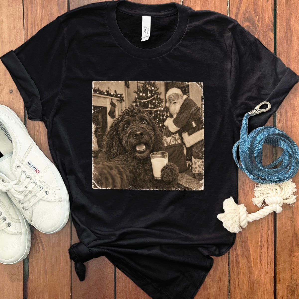 Black t-shirt featuring a vintage photo of a dark poodle holding milk with Santa in the background.