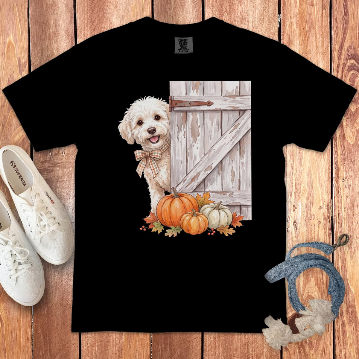 Black t-shirt with a fluffy white dog peeking from behind a rustic wooden door with pumpkins.